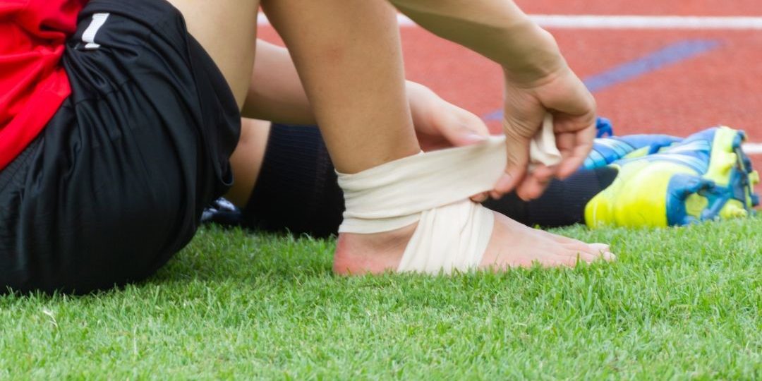 Sportsperson strapping their ankle.