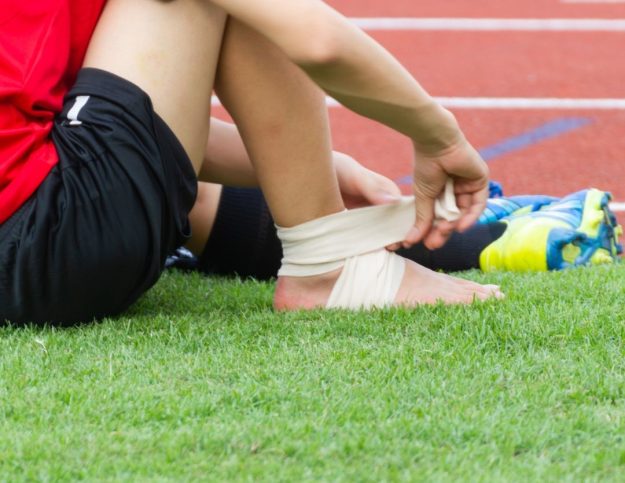 Sportsperson strapping their ankle.